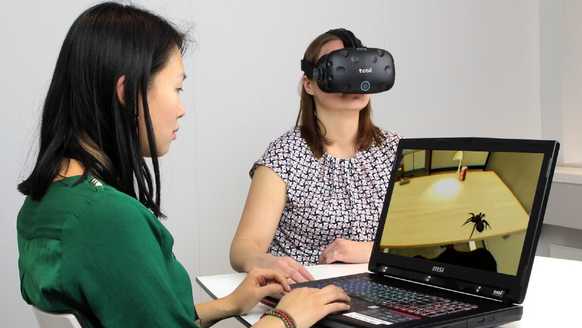 Persona asistiendo a otra en el tratamiento de aracnofobia mediante una simulación de RV